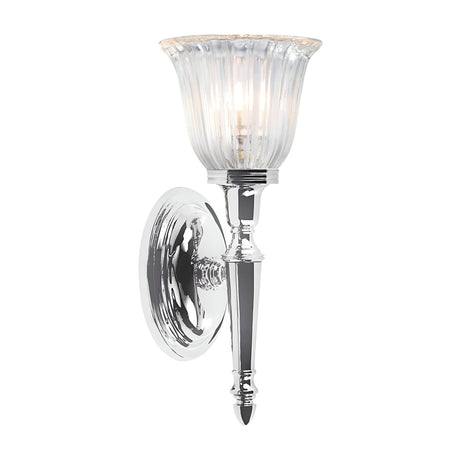 The Dryden-1 Wall Light in polished chrome showcases a fluted glass shade illuminated by a soft, glowing LED G9 lamp. Its modern design blends a reflective base with a vertical stem, making it an ideal addition to both contemporary and traditional interiors.