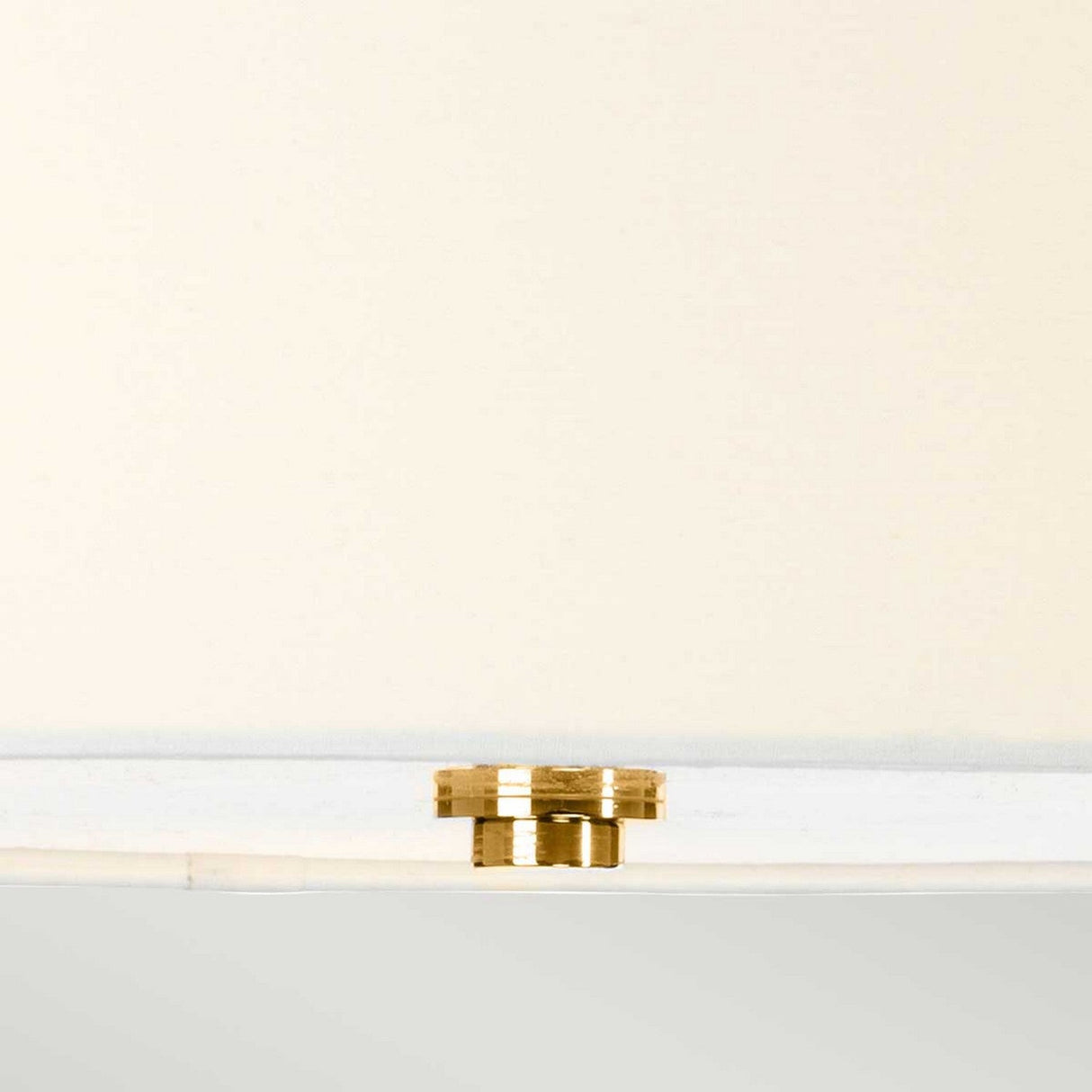 Close-up of the Falmouth 3 Light Semi Flush in French Gold on a smooth, light beige surface, showcasing its minimalist design and LED lighting technology.