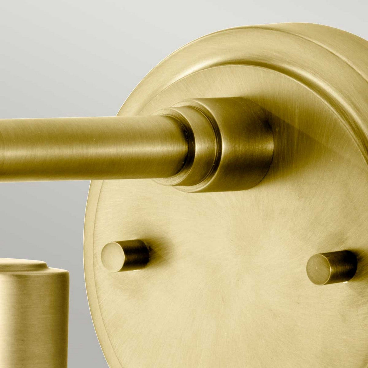 A close-up of the sleek and modern Morvah 1 Light Outdoor Wall Light in a brushed brass finish, featuring a cylindrical design. Its smooth, metallic surface reflects light beautifully, complementing vintage-inspired lighting against a muted gray background.
