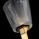A close-up showcases the luxurious Verity 1 Light Wall Light, featuring a crystal glass fixture with a diamond pattern set against a black background. Its elegant design is accentuated by the sleek, polished gold base.