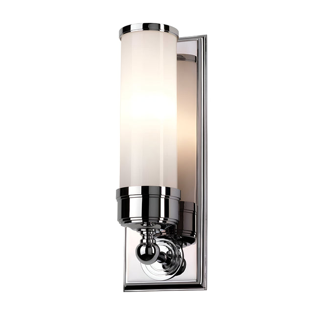 The Worcester 1 Light Wall Light in polished chrome features a cylindrical frosted glass shade that emits a soft, warm glow. With its sleek design, it embodies a modern yet transitional elegance, making it perfect for contemporary interiors.