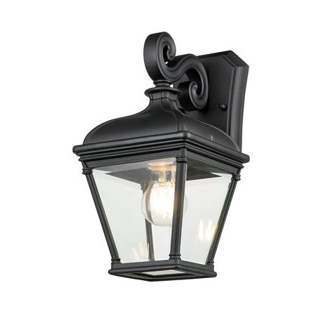 The Bayview 1 Light Outdoor Medium Wall Lantern - Black features a timeless design with a clear glass enclosure that showcases the visible bulb inside. Its graceful curves and traditional style create a striking piece of outdoor lighting.