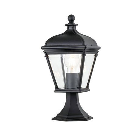 The Bayview 1 Light Medium Pedestal Lantern - Black is a vintage-style outdoor lighting fixture with a clear glass enclosure showcasing a visible light bulb, elegantly mounted on a decorative base. Its classical Georgian design brings timeless charm to any exterior space.