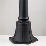 The Bayview 1 Light Medium Pillar Lantern in black showcases Georgian-inspired elegance with its robust, flared design and smooth finish. It is mounted on a flat white surface against a light gray background, making it ideal for sophisticated outdoor lighting.