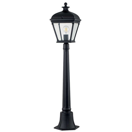 The Bayview 1 Light Medium Pillar Lantern - Black exudes elegance with its Georgian-inspired design, featuring a clear glass lantern and visible bulb that evoke a sense of timeless charm. Set against a plain white background, this lamp post captures the sophistication of classic outdoor lighting.