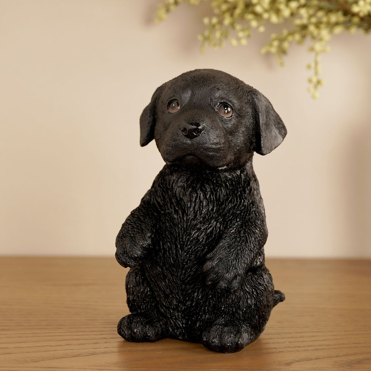 Black resin Labrador puppy figurine, 16cm, sitting up with paws raised and floppy ears, textured coat finish, displayed on a wooden surface against a neutral background.