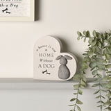 Grey MDF heart plaque with "A house is not a home without a dog" in black text, bone icons, and a raised textured dog figure, shown on a shelf with greenery.
