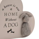 Heart-shaped MDF wall plaque in warm grey with black text reading "a house is not a home without a dog," two bone icons, and a raised textured grey dog figure with floppy ears.