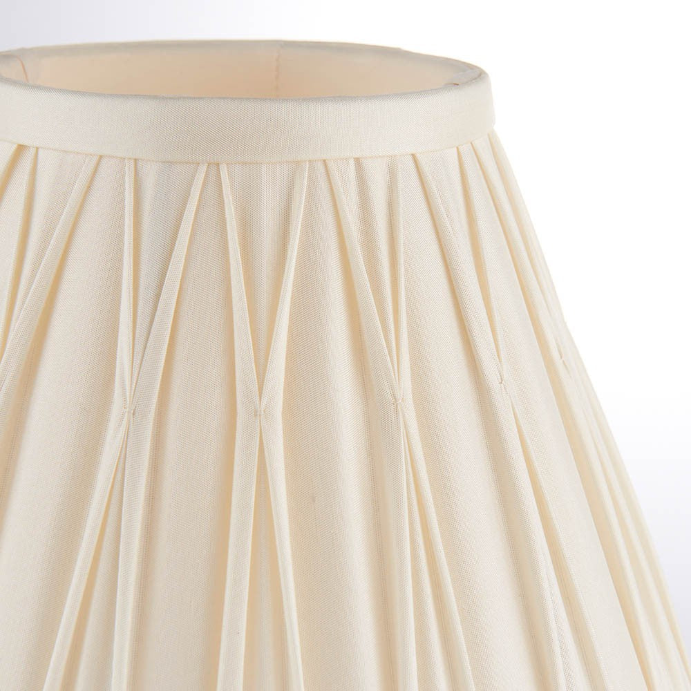 Close-up of the Bevdon 20cm tapered lamp shade in ivory silk, showing hand-stitched pinch pleats and a silk taped edge on a plain white background.