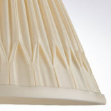 Close-up of Endon Bevdon 25cm tapered lamp shade in ivory silk, showing hand-stitched double pinch pleats and taped hem against a light background.