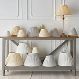 Endon Bevdon tapered lamp shades in ivory silk and grey tones with pinch pleat detailing, displayed across a two-tier grey console table.