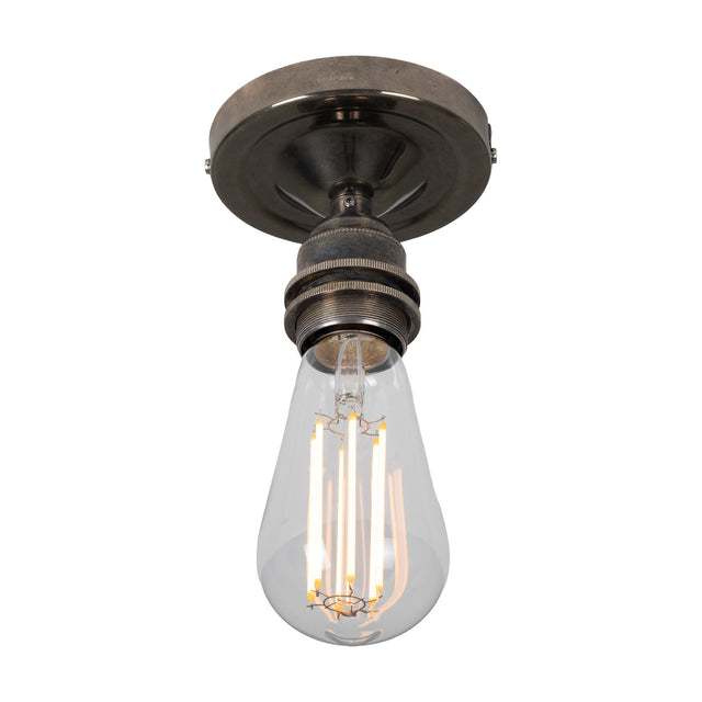 Bexter Vintage Brass Flush Ceiling Light with round ceiling plate and single knurled E27 lampholder holding a bare filament bulb, shown against a plain white background.