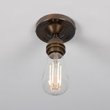 Bexter Vintage Brass Flush Ceiling Light with round aged-brass ceiling plate and knurled E27 lampholder holding an exposed filament bulb, shown against a plain white background.