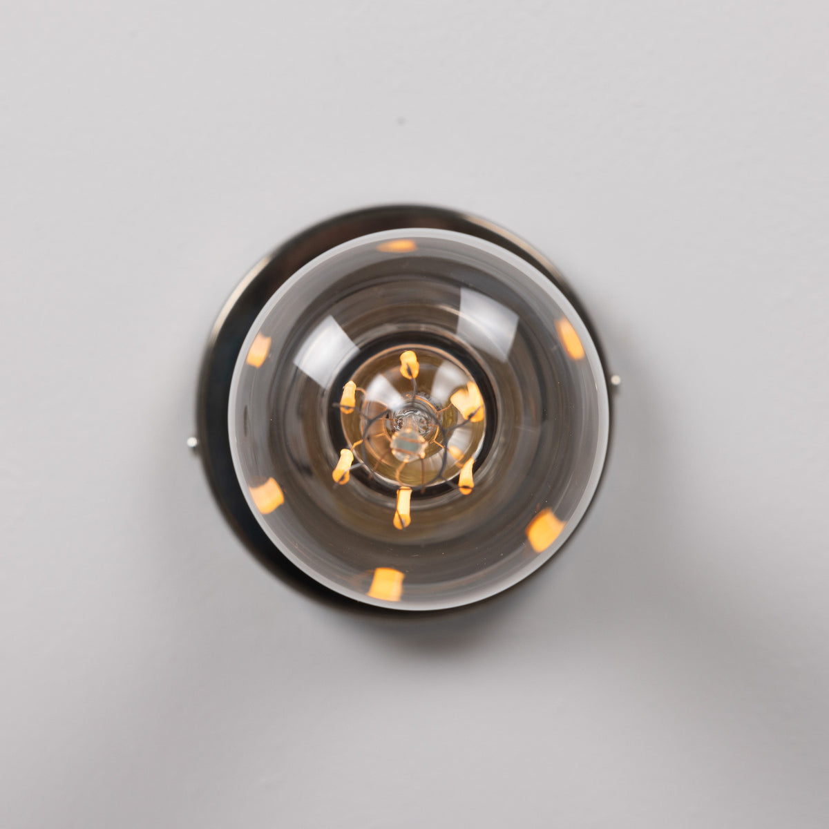 Bexter Vintage Brass Flush Ceiling Light, close-up view of the round brass plate and single E27 lampholder with knurled rings and bare bulb, shown against a plain light grey background.