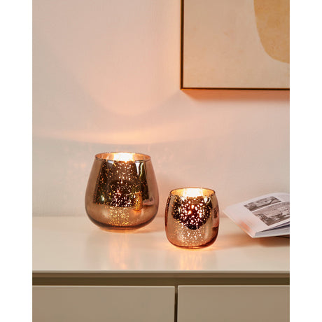 Bezamby glass tealight holders in brown and silver mercury finish with speckled mirrored surface, shown lit in two sizes on a sideboard.