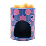Round ceramic wax melt burner in blue with pink smiley face pattern, arched tealight opening, and yellow wax melts in the top dish, shown on a white background.