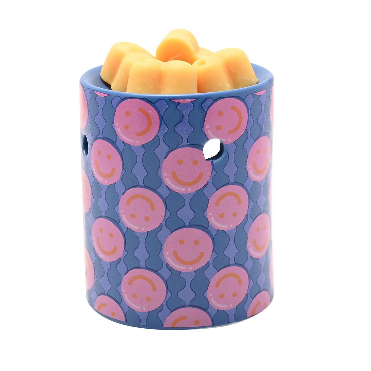Round blue ceramic wax melt burner with pink smiley face pattern, arched tealight opening, and orange wax melts in the top dish, shown on a white background.