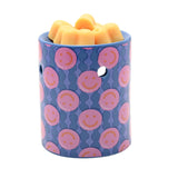 Round blue ceramic wax melt burner with pink smiley face pattern, arched tealight opening, and orange wax melts in the top dish, shown on a white background.