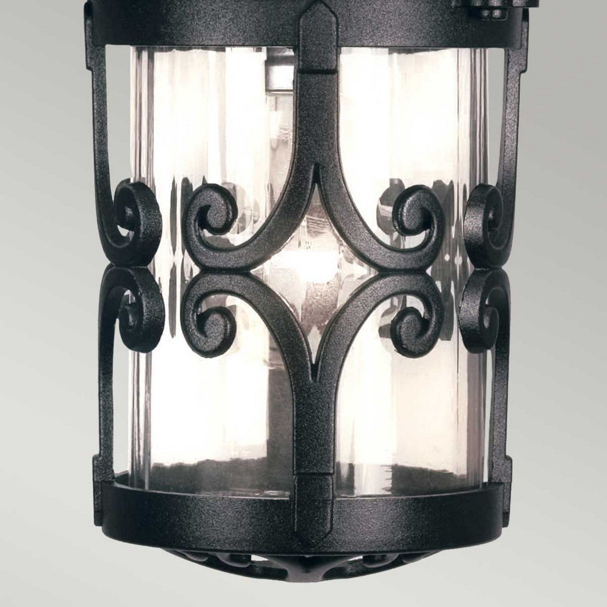 The Hereford 1 Light Outdoor Porch Chain Pendant in black features intricate black metal scrollwork and clear glass panes surrounding the light bulb inside. This timeless and decorative pendant brings elegance to any outdoor lighting arrangement.