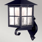 The Winchester 1 Light Outdoor Wall Up Light in black is a die-cast aluminium lantern that exudes historical elegance. Its timeless square shape, coupled with four textured glass panels, is mounted on the wall using an ornate, curved bracket.