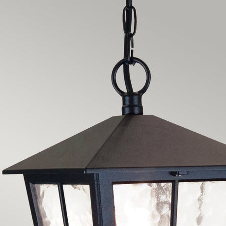 Here's a revised version of the sentence using the given product data:

Close-up of a Canterbury 1 Light Outdoor Chain Pendant - Black—a black, metal hanging lantern with a chain and ring at the top, featuring glass panels that beautifully diffuse light. It is perfect for outdoor lighting and stands out against the soft gray background.