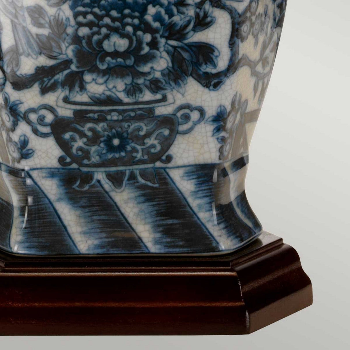 A close-up of a blue and white ceramic vase with intricate floral patterns highlights traditional Chinese craftsmanship, much like the artistry seen in the elegant Blue Hex Table Lamp. The porcelain base is gracefully perched on a dark wooden stand, enhancing its exquisite design.