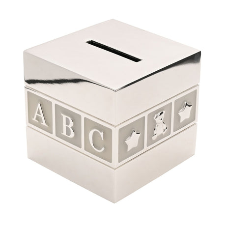 Silverplated cube money box styled as a baby building block, with a coin slot on top and a grey panel band showing raised ABC letters, a star and a teddy bear, on a plain white background.