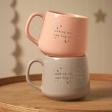 Set of 2 porcelain mugs in pink and grey, stacked with rounded handles, star and moon details, and "making memories, one hug at a time" script.