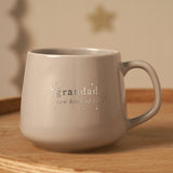 Grey stoneware mug with silver "grandad, a new kind of love" lettering, stars and crescent moon design, curved handle, shown on a wooden surface.