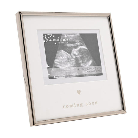 Square silver metal photo frame with white mount holding a baby scan image, small heart detail and "coming soon" text below, on a plain white background.