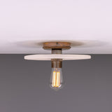 Bog Oak ceramic ceiling light with a flat round matt white striped disc and brass lampholder holding a bare bulb, shown against a plain background.
