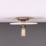 Bog Oak ceramic ceiling light with a flat round matt white striped disc and brass fitting, holding a single exposed bulb, shown against a plain background.