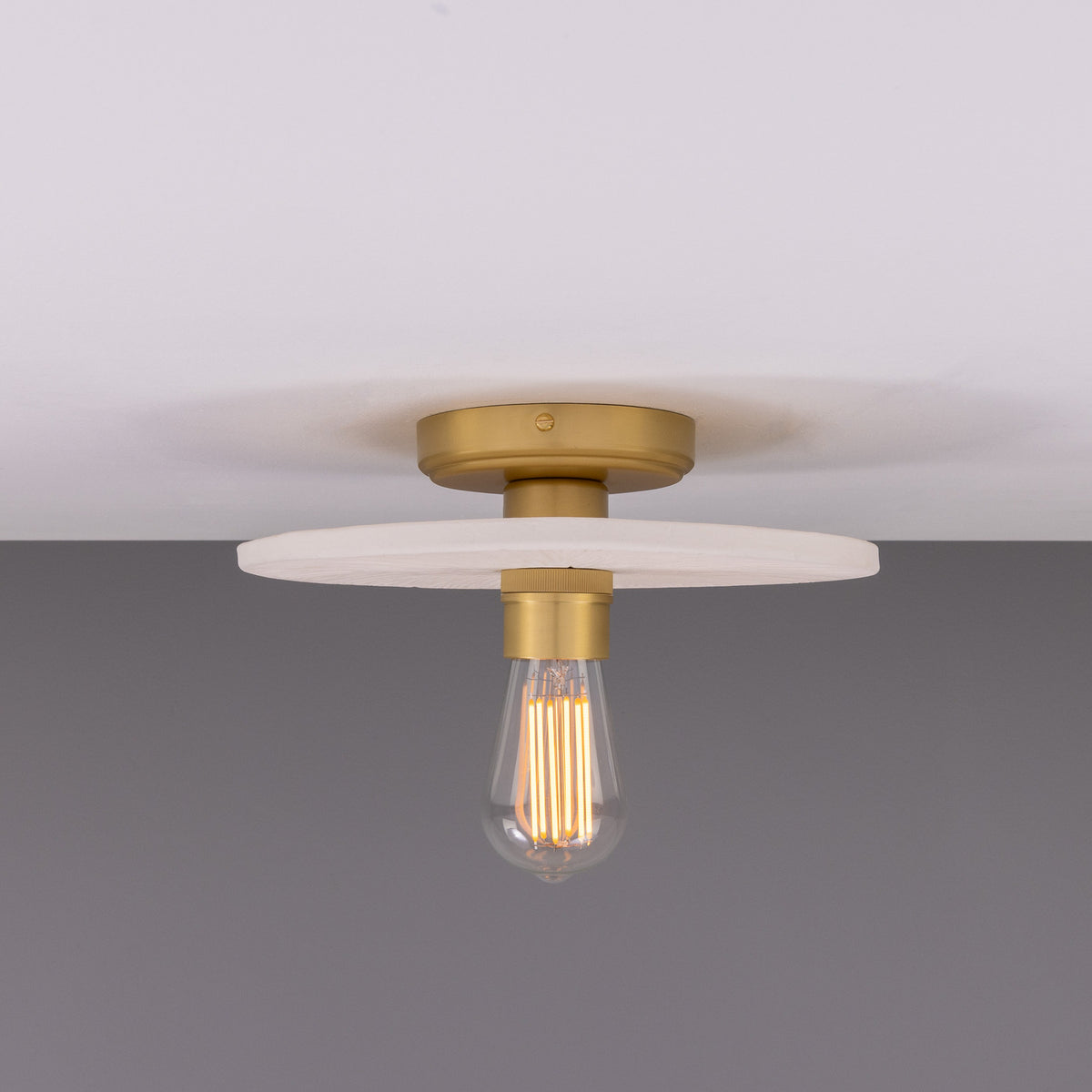 Bog Oak ceramic ceiling light with a flat round matt white striped disc, brass ceiling mount and lampholder, fitted with a bare bulb, shown against a plain grey background.