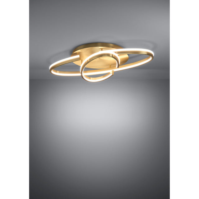 Bogado LED flush ceiling light in gold, featuring an oval ring and smaller round loop in steel with a glowing white diffuser, mounted on a round ceiling plate against a grey background.