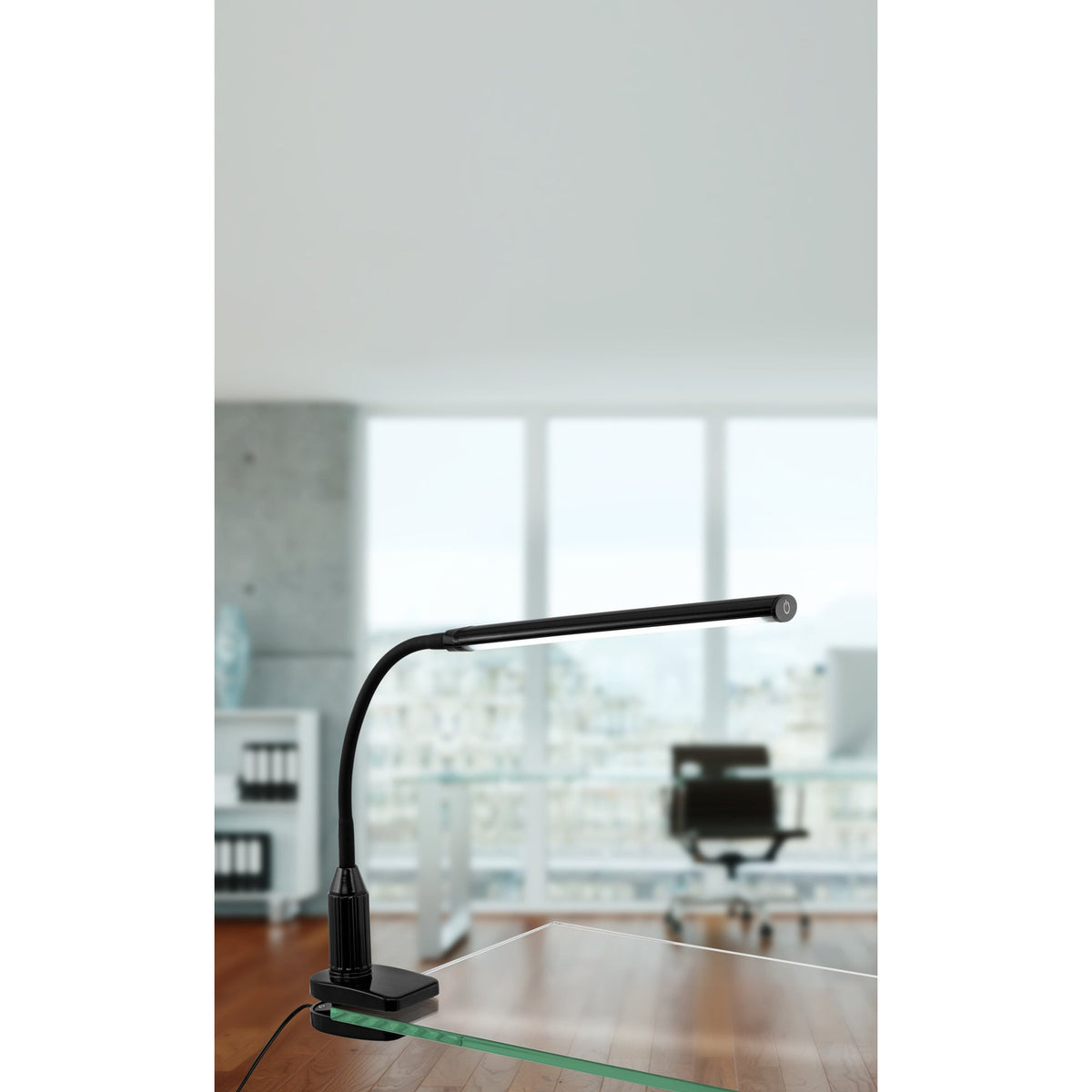 Bolbanne black clamp desk lamp with slim bar-shaped LED head and flexible gooseneck, clamped to a glass desk edge in a bright office setting.