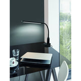 Bolbanne Clamp Lamp in black, with a slim bar-shaped LED head and flexible gooseneck, clamped to a glass desk edge in a study setting with cool white light illuminating the wall.