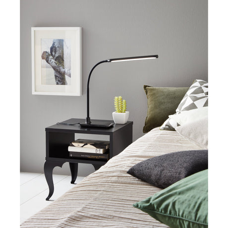 Bolbanne LED touch table lamp in black on a bedside table, with flexible gooseneck and long bar head, shown beside books and a small cactus in a bedroom setting.