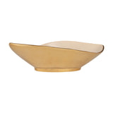 Bongosi decorative bowl, a long leaf-shaped aluminium dish with pointed ends, gold exterior and foot, glossy cream interior, on a plain white background.