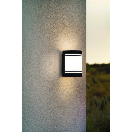Bonvenne Outdoor Wall Light in black steel with a white satin glass diffuser and banded horizontal bars, mounted on a textured wall and illuminated up and down.