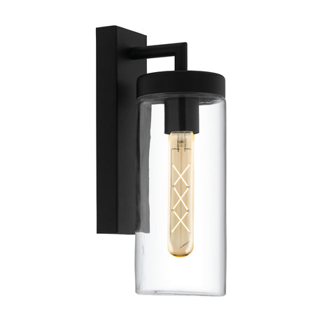 Bovolone outdoor wall light with a black steel backplate and squared arm holding a clear glass cylinder shade, shown with visible amber bulb on a plain white background.