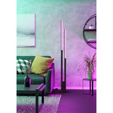 Branessa Smart Colour Changing LED Floor Lamp in black, two slim aluminium uprights of different heights with glowing white diffuser strips, shown in a living room with purple ambient lighting.