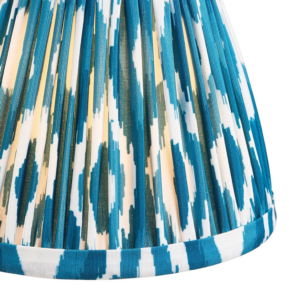 Close-up of Endon Brenwell 16cm tapered lamp shade in marlin blue, showing pleated faux silk with blue and white ikat print and taped edge trim.