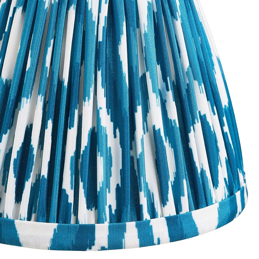 Close-up of Endon Brenwell 16cm tapered lamp shade in marlin blue, showing pleated faux silk with ikat pattern and taped edge trim.