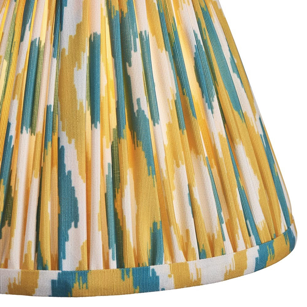 Close-up of Endon Brenwell 16cm tapered lamp shade in pleated faux silk with a yellow and jade ikat pattern and taped edge trim.