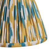 Close-up of Endon Brenwell 16cm tapered lamp shade in pleated faux silk with a yellow and jade ikat print and taped edge trim.