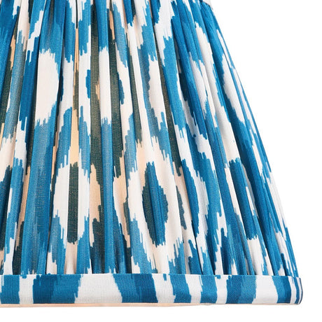 Close-up of Endon Brenwell 20cm tapered lamp shade in marlin blue, showing pleated faux silk with ikat pattern in blue, white and green tones.