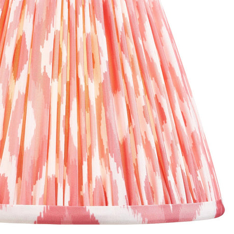 Close-up of Endon Brenwell 25cm tapered lamp shade in coral pink, showing pleated faux silk with ikat pattern and taped edge detailing.