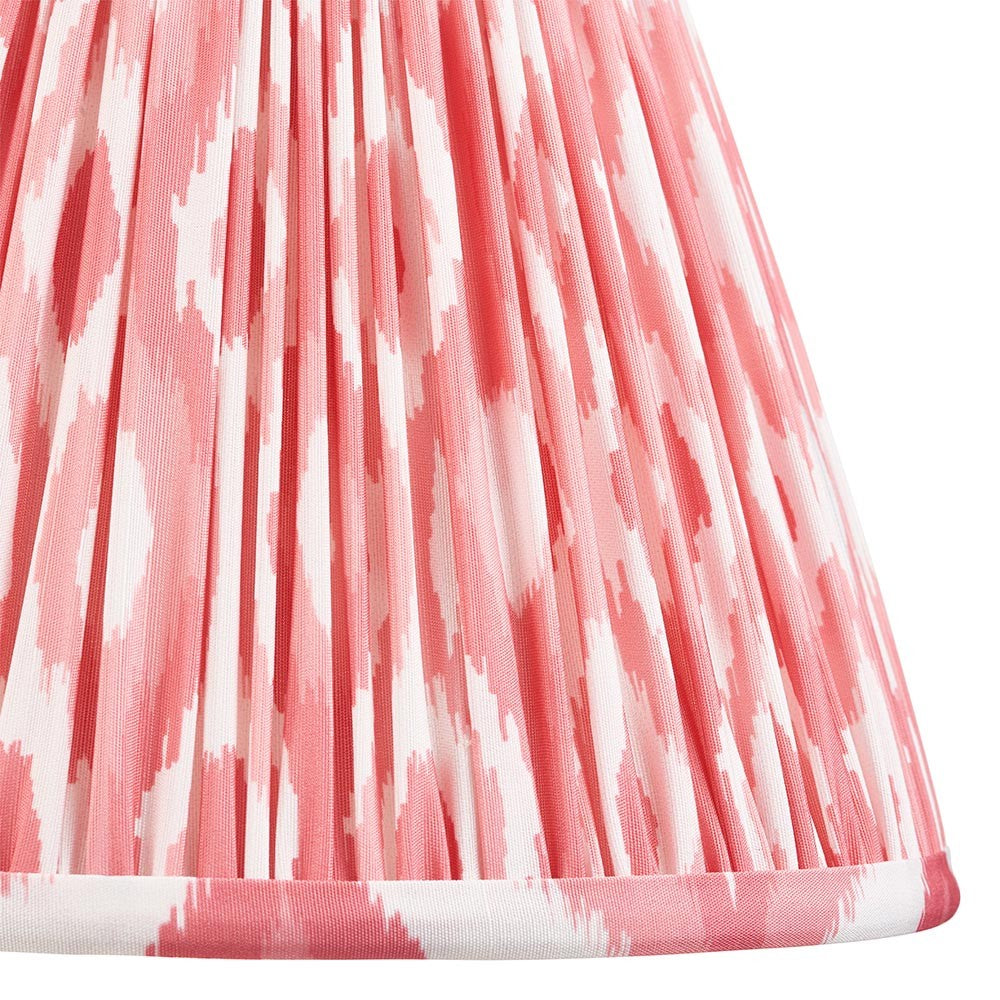 Close-up of Endon Brenwell 25cm tapered lamp shade in coral pink and white ikat print on gathered pleated faux silk with taped edge trim.