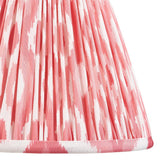 Close-up of Endon Brenwell 25cm tapered lamp shade in coral pink and white ikat print on gathered pleated faux silk with taped edge trim.