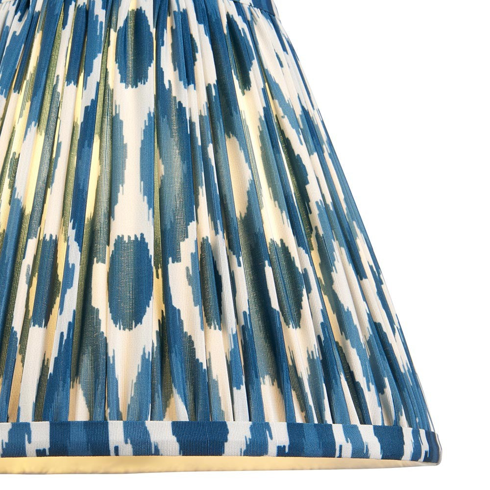 Close-up of Endon Brenwell 25cm tapered lamp shade in marlin blue, showing pleated faux silk with blue and white ikat pattern and taped edge trim.